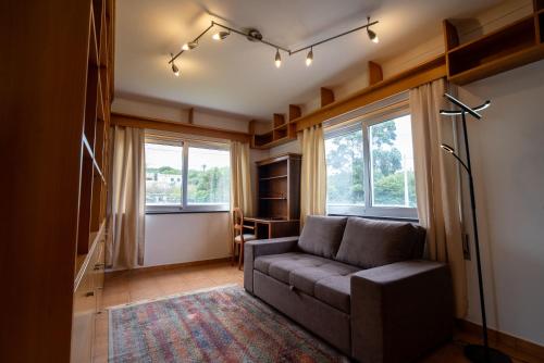 a living room with a couch and two windows at Vila Canada das Vinhas in Porto Martins