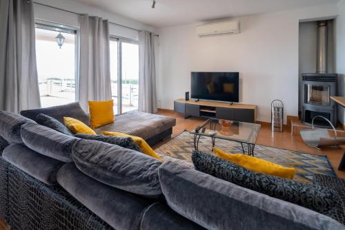 a living room with a large couch and a television at Vila Canada das Vinhas in Porto Martins