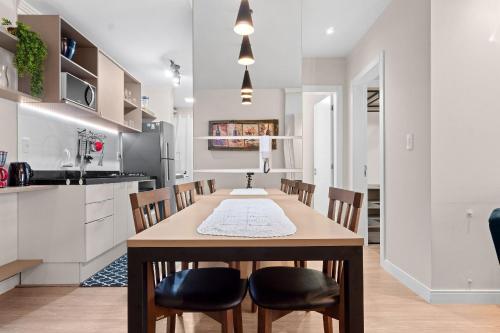 a kitchen and dining room with a wooden table and chairs at Campos de Canela 1 dorm na Rua Coberta by Achei in Canela