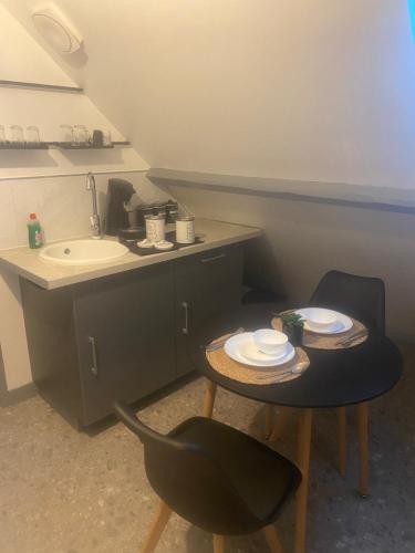 La salle de bains est pourvue de 2 chaises, d'un lavabo et d'une table. dans l'établissement Appartement climatisé avec jaccuzi, à La Chapelle-Saint-Mesmin