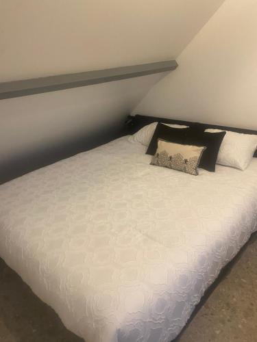 un lit avec des draps blancs et des oreillers dans une chambre dans l'établissement Appartement climatisé avec jaccuzi, à La Chapelle-Saint-Mesmin