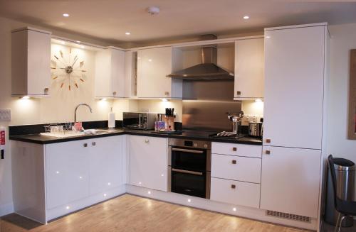 a kitchen with white cabinets and black counter tops at House of Fisher - Central Point in Basingstoke