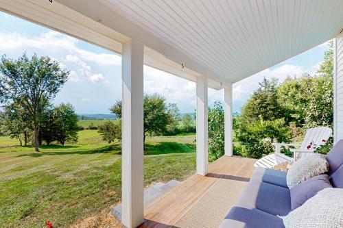 a porch with a blue couch and a view of a field at Cider Hill Haven in New Haven