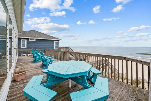 a deck with blue picnic tables and the beach at Shore is Something in North Topsail Beach