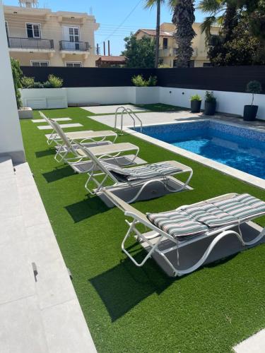 a row of lounge chairs next to a swimming pool at Pervolia Oasis Villa in Kiti