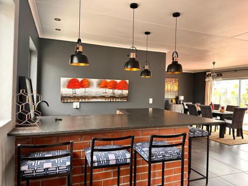 a kitchen with a bar with chairs and lights at West Beach Luxury Apartment in Bloubergstrand
