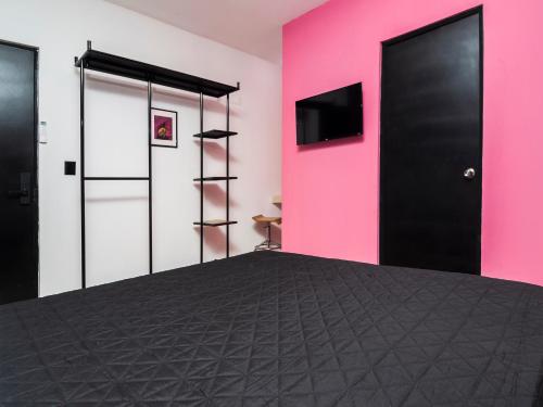 a room with a pink wall and a black door at Adhoc Cintermex in Monterrey