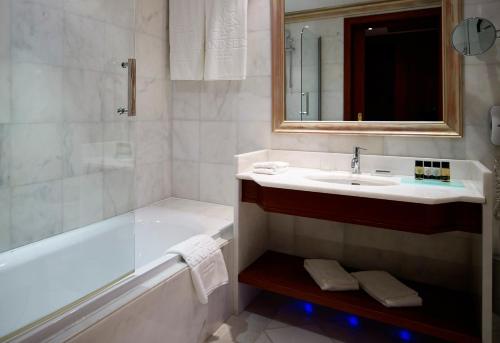 a bathroom with a tub and a sink and a mirror at Grand Serai Congress and Spa in Ioannina