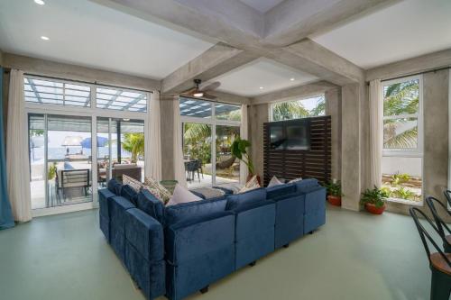 a living room with a blue couch and windows at Oceanfront 3 Bedroom - Conmigo Villas South in Maya Beach