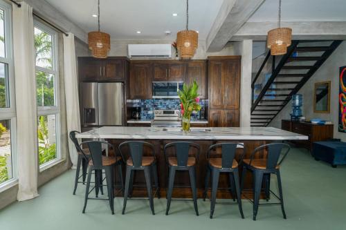 a kitchen with a large island with chairs around it at Oceanfront 3 Bedroom - Conmigo Villas South in Maya Beach