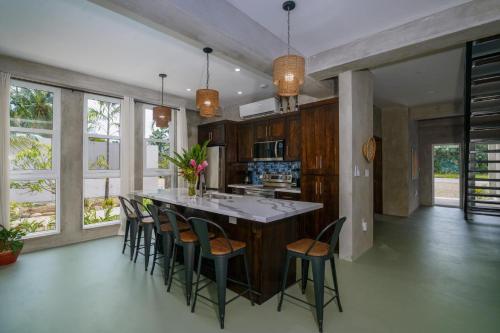 a kitchen with a large island with chairs in it at Oceanfront 3 Bedroom - Conmigo Villas South in Maya Beach