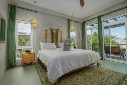 a bedroom with a large white bed and windows at Oceanfront 3 Bedroom - Conmigo Villas North in Maya Beach