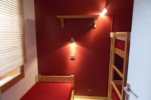 Cette chambre dispose d'un mur rouge et de lits superposés. dans l'établissement Résidence Comete - 2 Pièces pour 5 Personnes 63, à Mâcot La Plagne