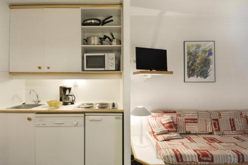 - une petite cuisine avec un lit et un four micro-ondes dans l'établissement Résidence Licorne - Studio pour 4 Personnes 99, à Mâcot La Plagne