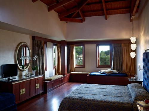 a bedroom with a bed and a couch and windows at Grand Serai Congress and Spa in Ioannina