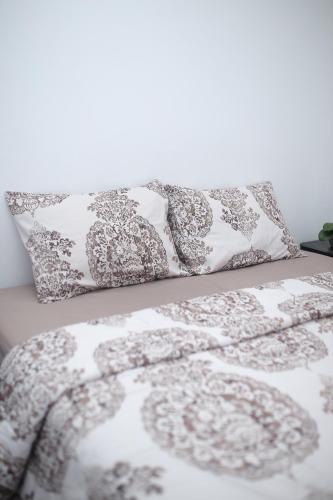 a bed with a gray and white comforter and pillows at Villa indah in Beber