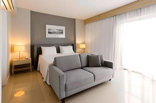 a bedroom with a bed and a couch at Flats Aconchegantes na Barra da Tijuca, Link Stay in Rio de Janeiro