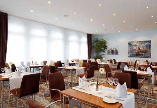 ein Restaurant mit Tischen und Stühlen in einem Zimmer in der Unterkunft Seaside Residenz Hotel Chemnitz in Chemnitz