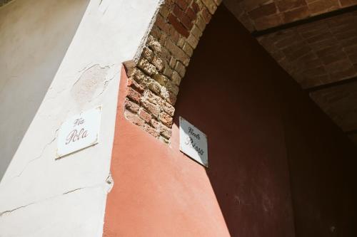 a brick wall with signs on the side of a building at Vicolo Al Castello - Langhe e Monferrato Suites in Costigliole dʼAsti