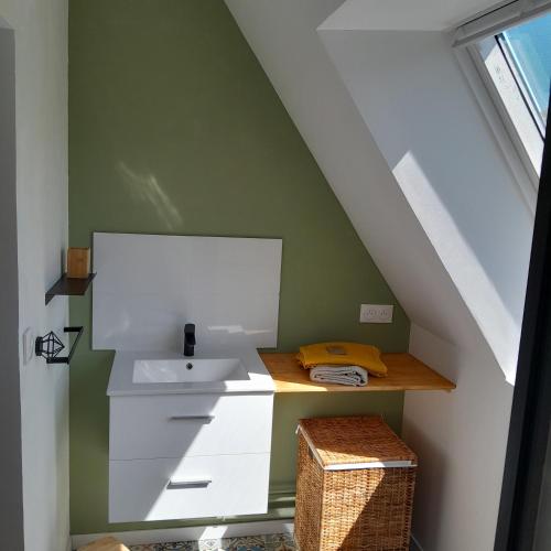 - une salle de bains mansardée pourvue d'un lavabo et d'un comptoir dans l'établissement La Charretterie Cœur du village typique Normand, à Saint-Christophe-sur-Condé
