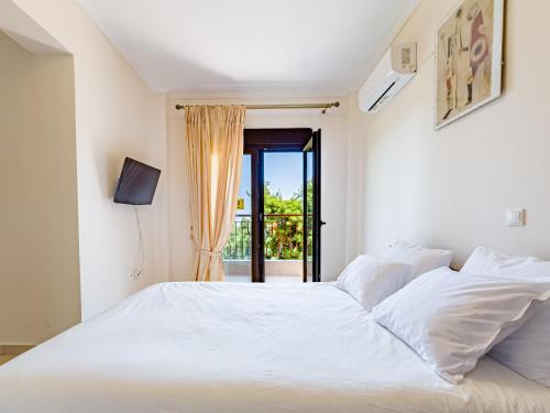 a white bed in a room with a window at Holiday home with panoramic view of the forest in Polykhrono