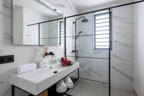 Un baño blanco con lavabo y ducha. en Jan thiel Modern Apartments Curacao, en Jan Thiel