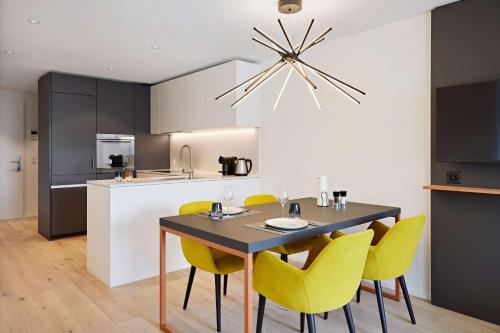 a kitchen with a dining table and yellow chairs at Essential by Dorint Interlaken - New Opening in Interlaken