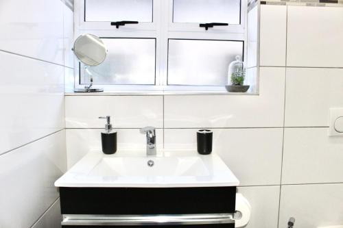 a white bathroom with a sink and a window at Sea and Mountain View Apartment in Cape Town