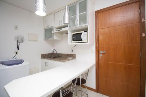 a kitchen with a white counter and a wooden door at OZPED Flats Particulares Edifício Life Resort in Brasilia