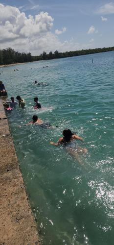 a group of people swimming in a body of water at Ocean Peak Home in Fajardo