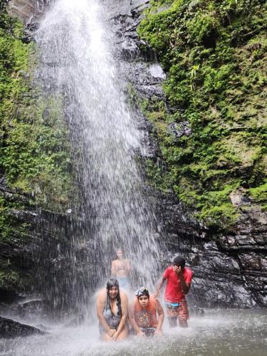 three men in the water near a waterfall at Ocean Peak Home in Fajardo
