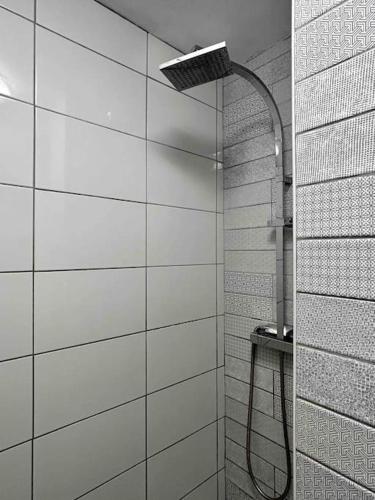 La salle de bains est pourvue d'une douche avec un tuyau et de carrelage blanc. dans l'établissement Ile tudy Bord de plage et farniente en terrasse Appt classé 3 étoiles, à l'Île-Tudy