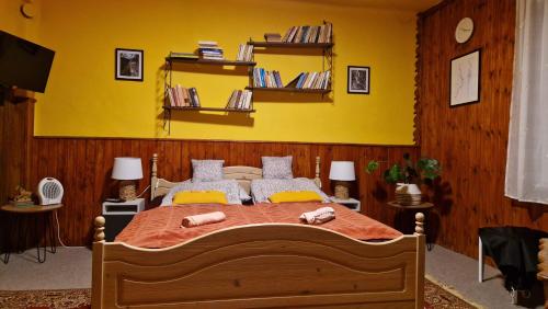 a bedroom with a large bed with a yellow wall at Garan Vendégház in Jósvafő