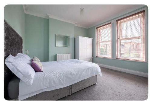 a bedroom with a large bed with blue walls and windows at Beautiful Garden Flat in Bournemouth - First Floor in Bournemouth