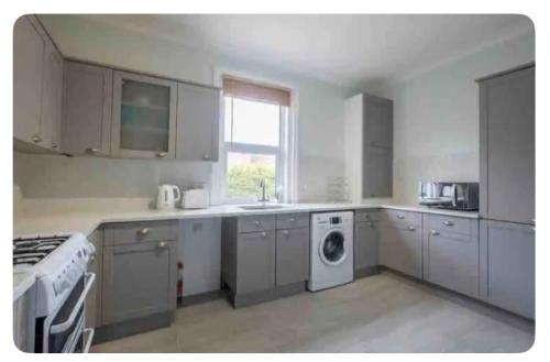 a kitchen with white cabinets and a washing machine at Beautiful Garden Flat in Bournemouth - First Floor in Bournemouth