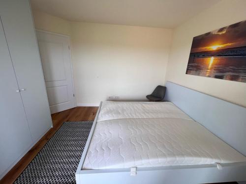 a white bed in a room with a painting on the wall at Ferienwohnung-Frees-Mooi in Neßmersiel