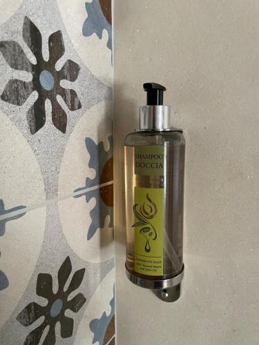 a bottle of soap sitting next to a wall at ALOE Comfort Rooms in Pescara