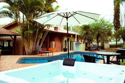 a pool with an umbrella and a table and chairs at SR Brotas in Brotas