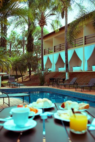 a table with plates of food next to a swimming pool at SR Brotas in Brotas