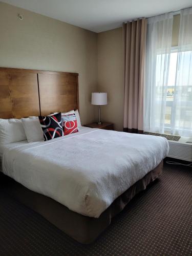 a large bed in a hotel room with a window at The Kanata Bonnyville in Bonnyville