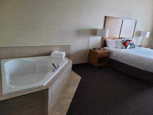 a bathroom with a bath tub next to a bed at The Kanata Bonnyville in Bonnyville