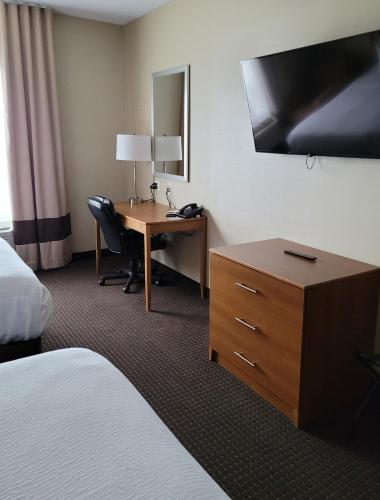 a hotel room with a desk and a bed and a room with a bed at The Kanata Bonnyville in Bonnyville