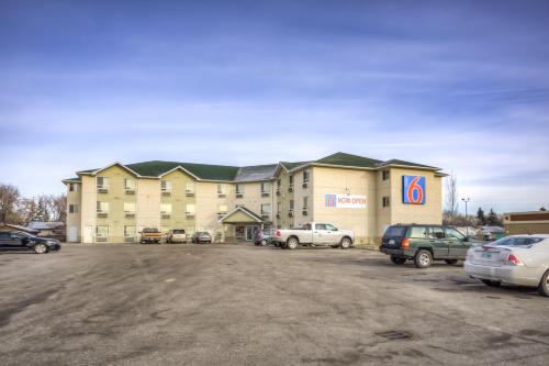 a large building with cars parked in a parking lot at Motel 6-Regina, SK in Regina