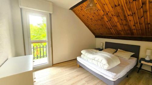 une chambre avec un lit avec un plafond en bois et une fenêtre dans l'établissement Résidence Les Maisonnettes - GRAND APPARTEMENT AU CALME - 6/7 PERS MAE-4661, à Puy-Saint-Vincent