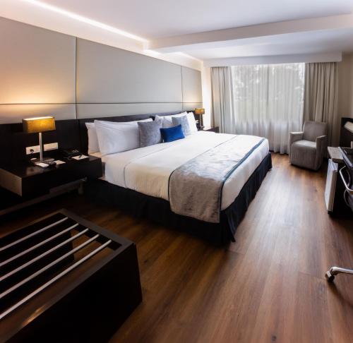 a hotel room with a large bed and a chair at Oro Verde Cuenca in Cuenca