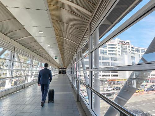 a man walking down a walkway with a suitcase at PARKROYAL Melbourne Airport in Melbourne