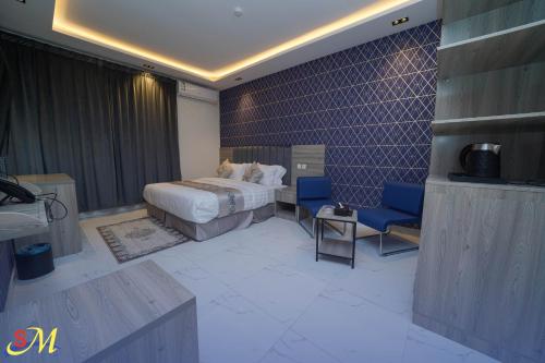 a bedroom with a bed and a blue chair at شقق اس ام للشقق الفندقية in Hafr Al Baten