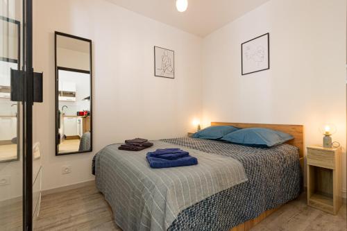 une chambre avec un lit avec des oreillers bleus et un miroir dans l'établissement Cirrus Coeur Historique, à Montpellier