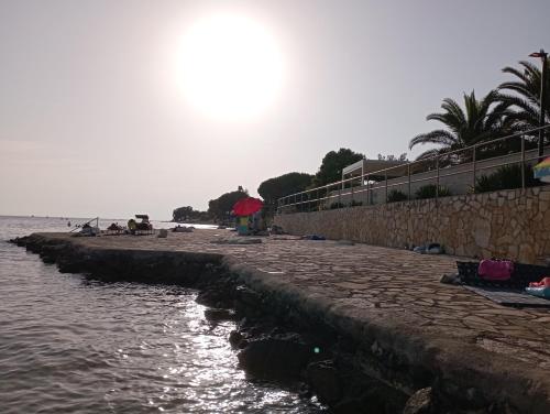 a beach with a retaining wall and the water at Apartman Sole in Karigador