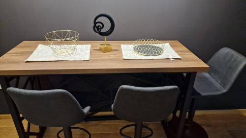 a wooden table with chairs and baskets on it at LUXURY APARTMAN ELENI ROOMS oaza mira i tišine u centru Vrnjačke banje in Vrnjačka Banja